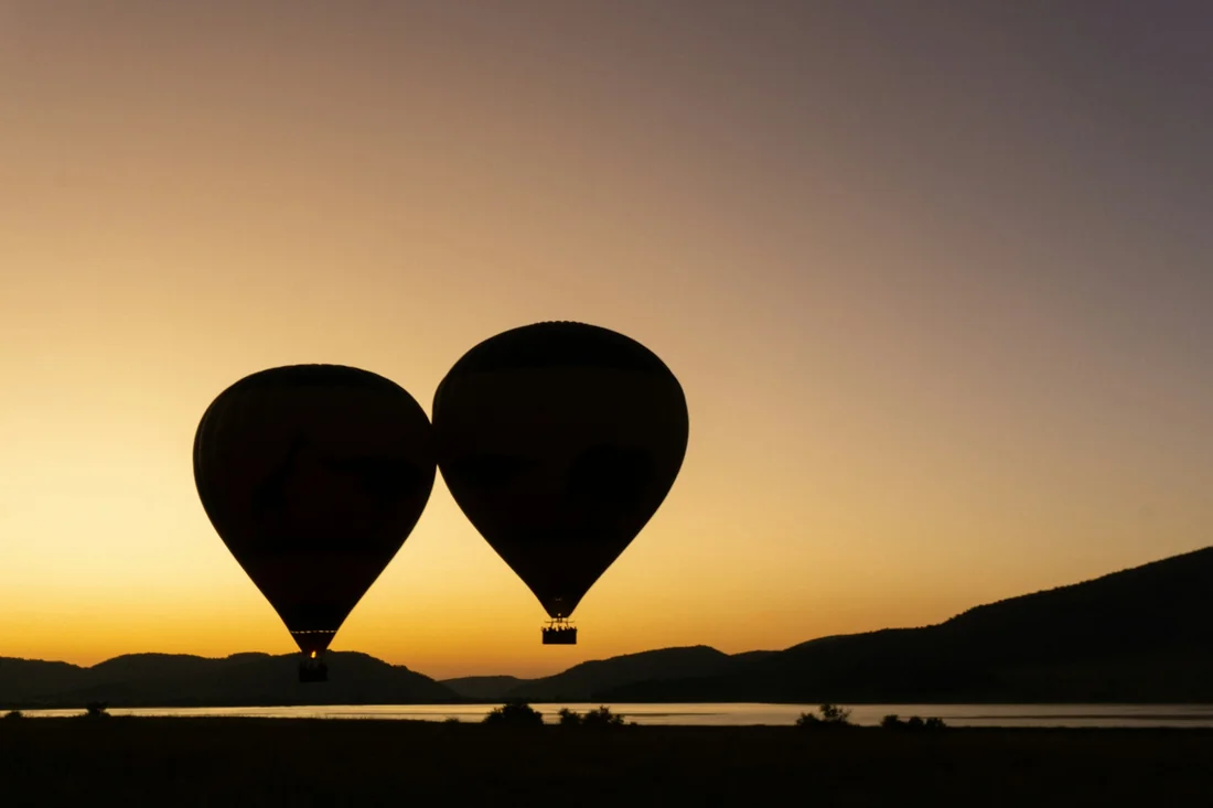 Two balloons flying together at sunrise